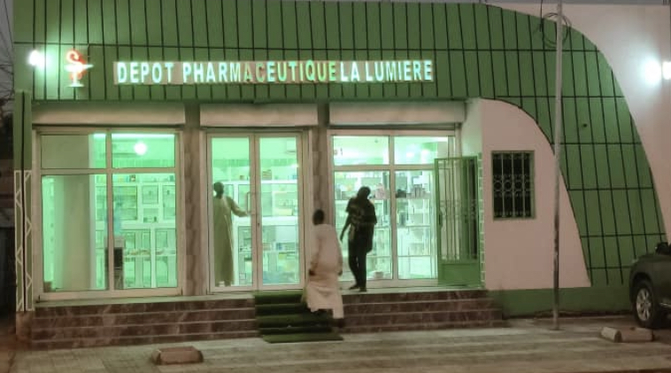 Façade de la Pharmacie La Lumière illuminée de nuit, quartier Djari, N'Djaména